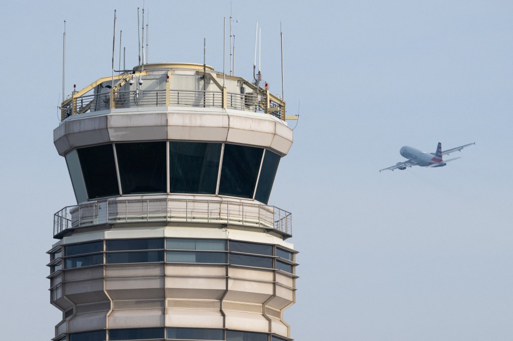 Air traffic control tower with an American Airlines plane taking off.