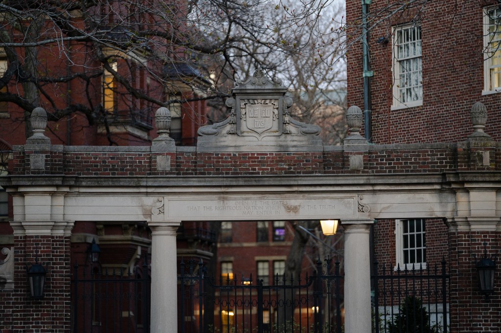 Stone archway with 'Veritas' written on a gate at Harvard University, representing a critical moment in 2025 when federal funding was frozen by the Trump Administration