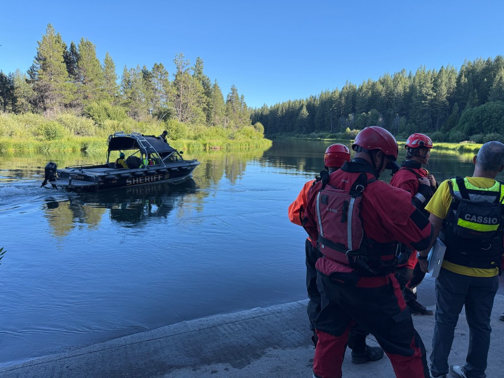 Rescuers in a sheriff's boat search for missing people after a waterfall accident.