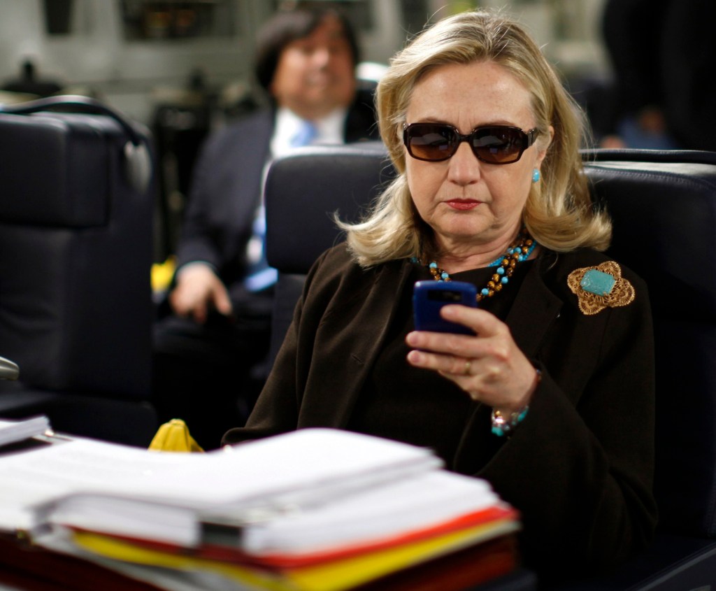 Hillary Clinton using a PDA on a plane.