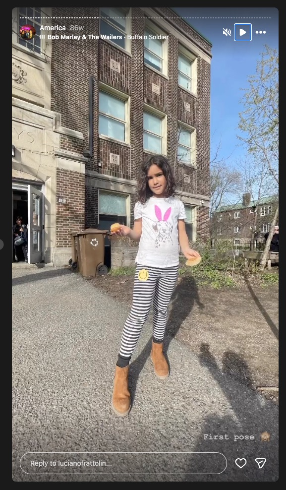 Girl holding two pastries in front of a brick building.