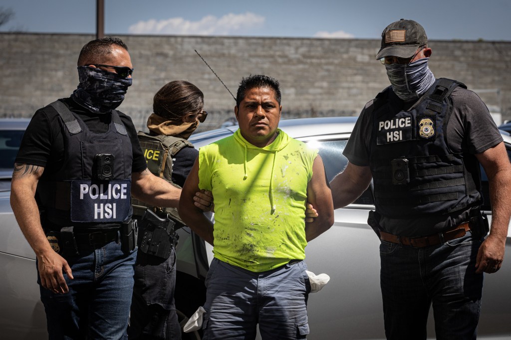 A man in handcuffs being escorted by Homeland Security Investigations agents.
