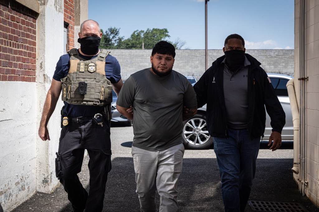 A man in handcuffs escorted by two officers.