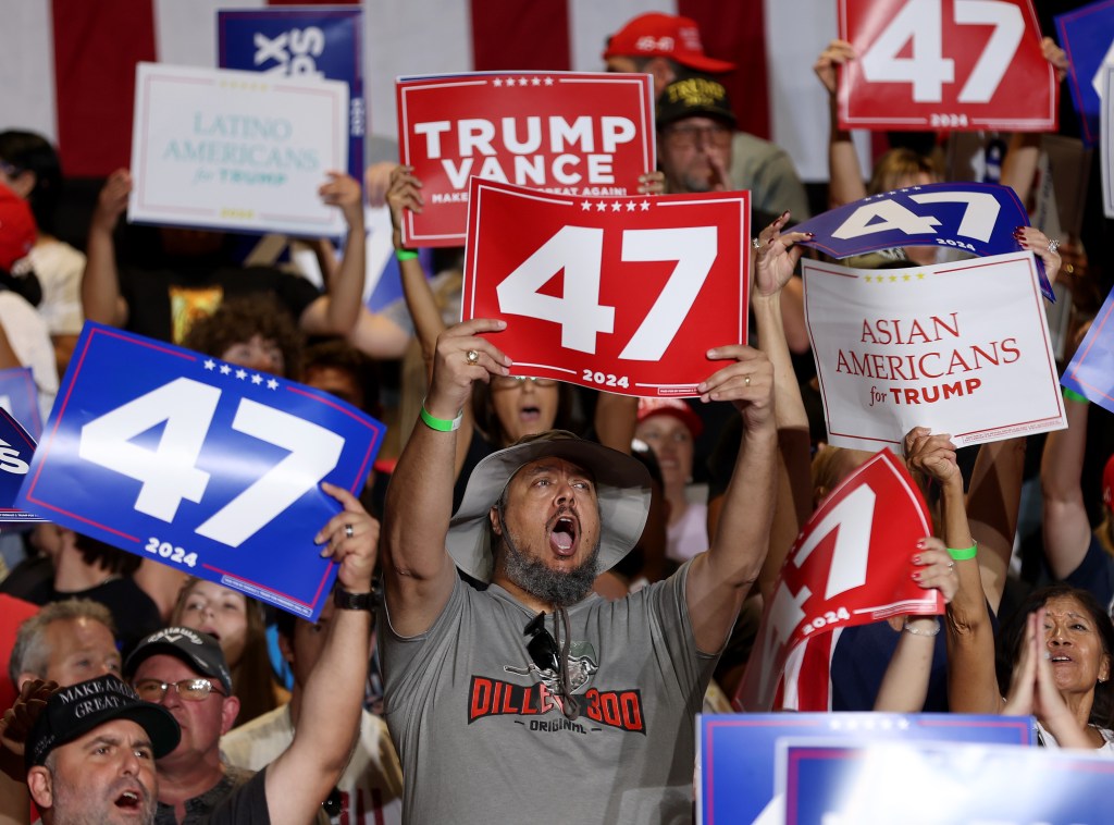 Supporters at a Donald Trump rally hold signs.