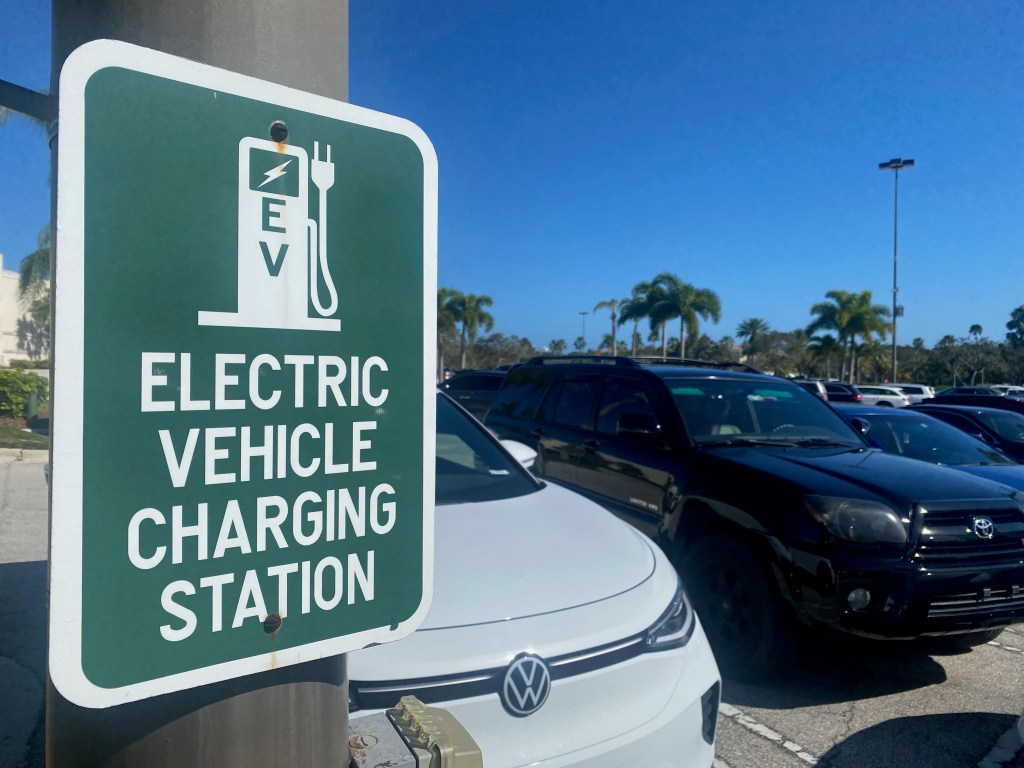 Electric vehicle charging station sign in a parking lot.