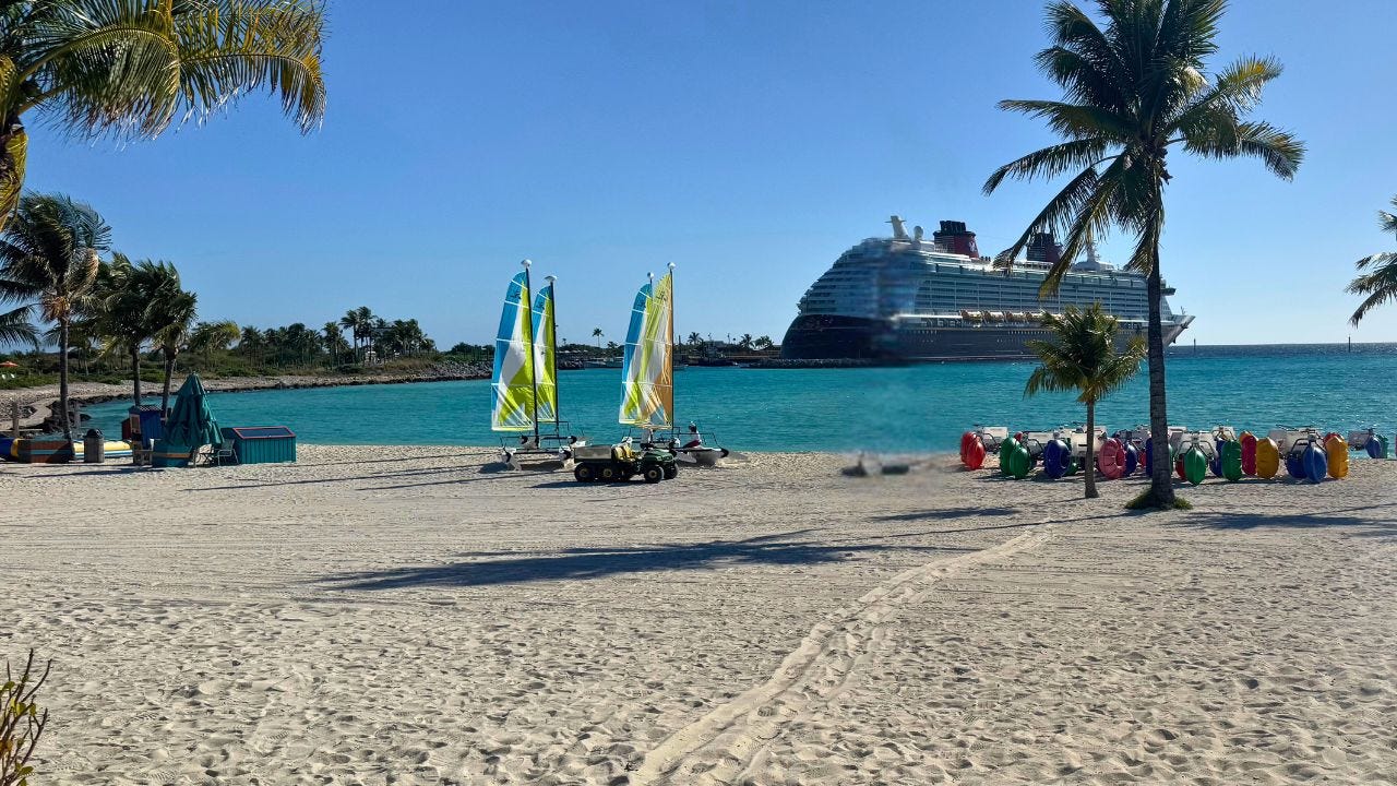 Beach with view behind it of Disney Dream docked at at Castaway Cay