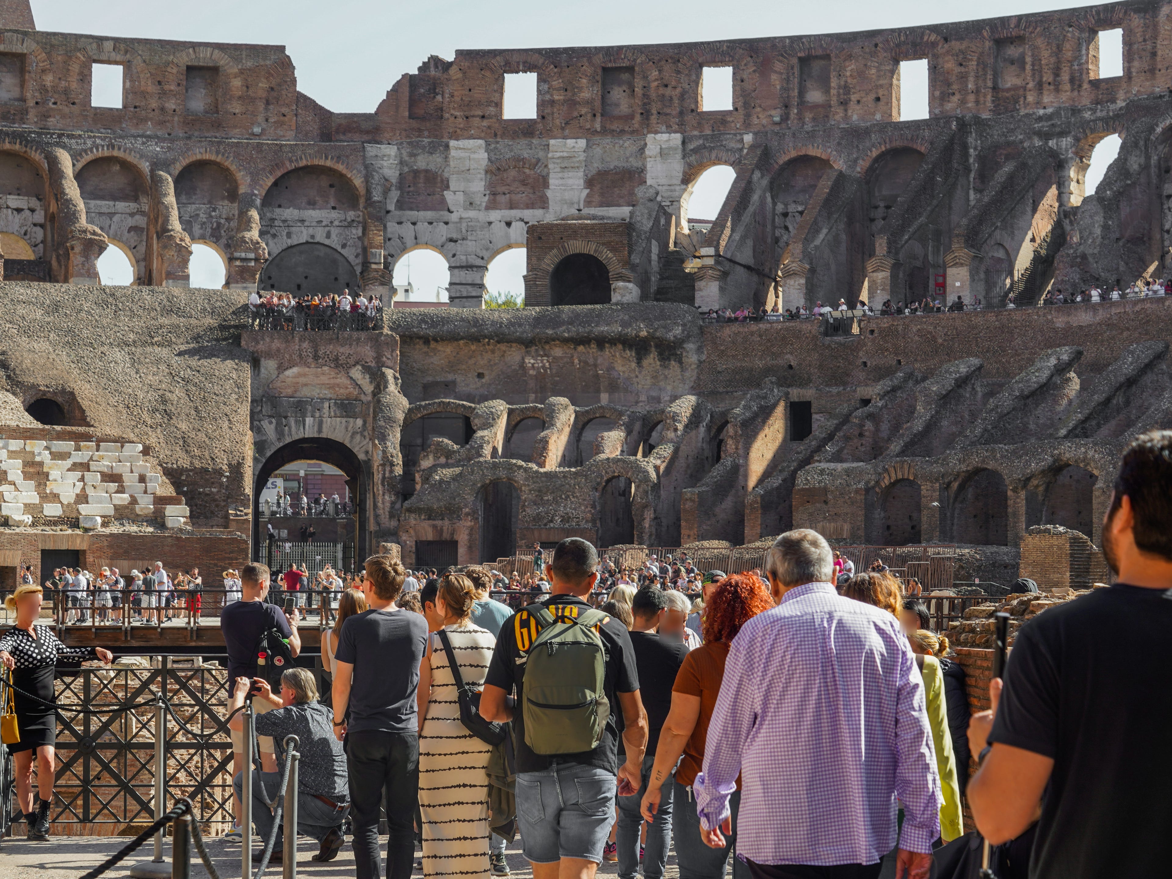 Crowds of people stand in front of the arena at the Colosseum in Rome