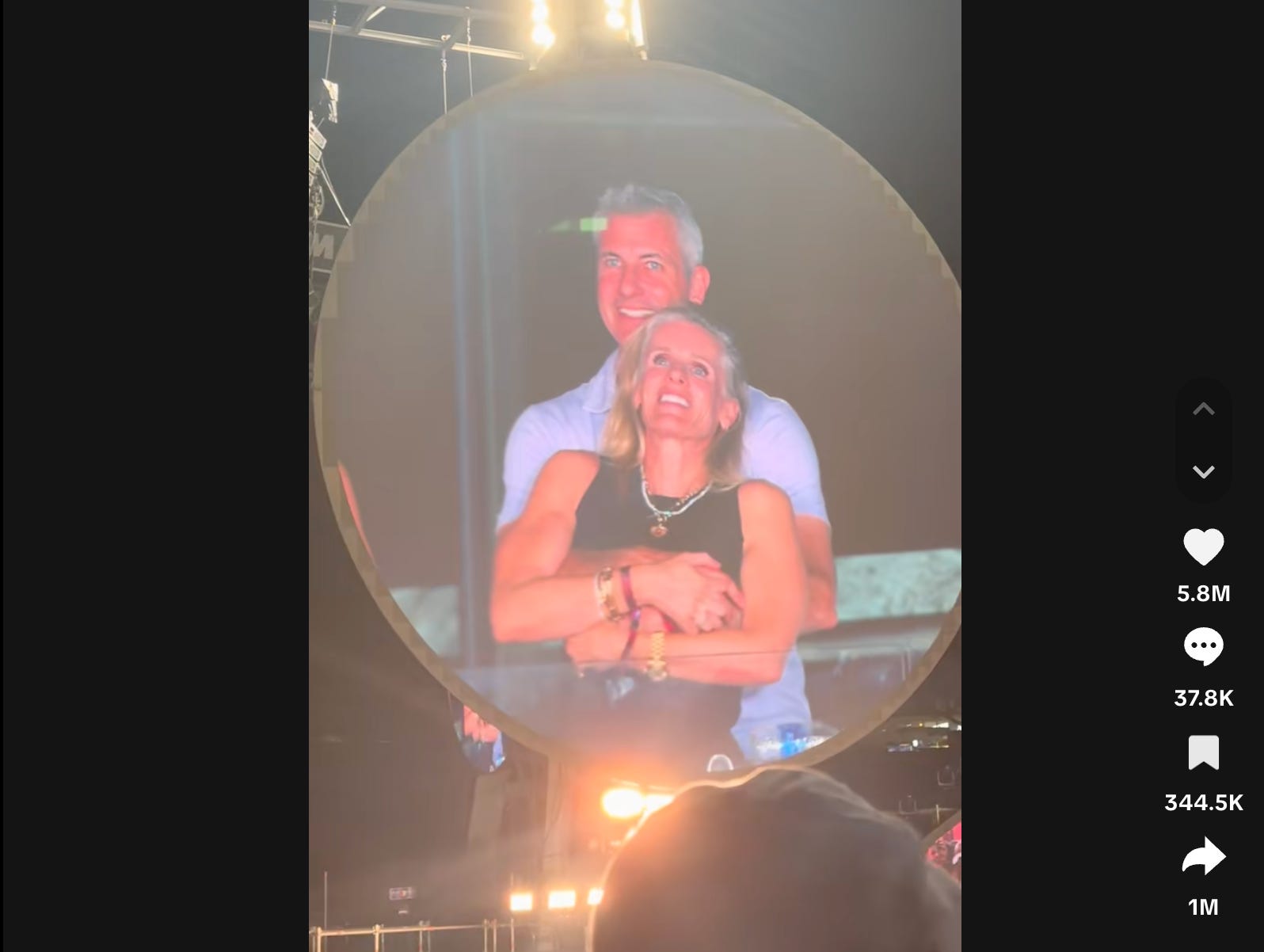 A screenshot from a TikTok of a man and woman embracing while watching a concert, shown on a "kiss cam"