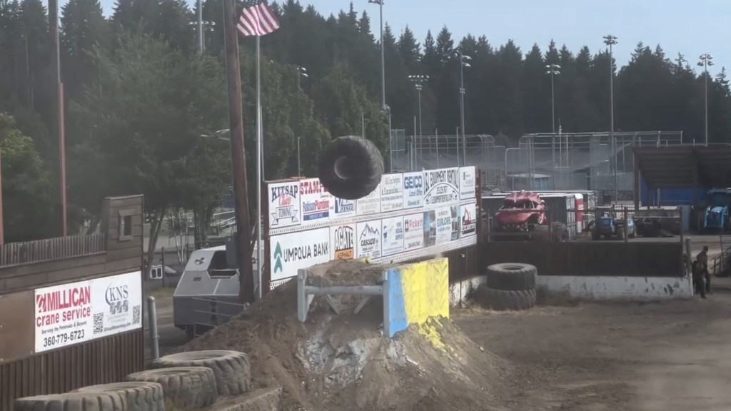 Monster truck tire flying through the air at a show.
