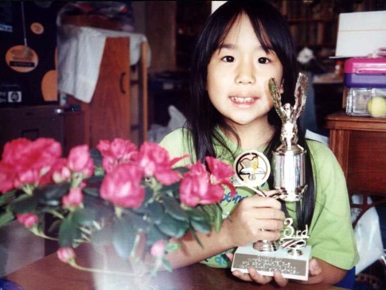 Old photo of a young girl holding a third-place award.