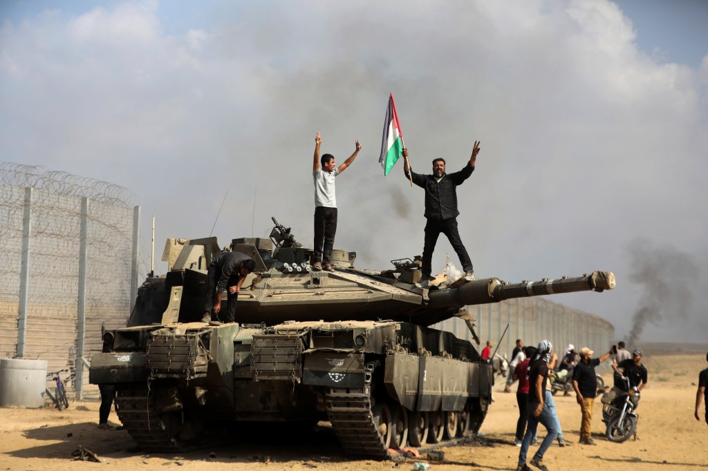 Palestinians celebrating on top of a destroyed Israeli tank.