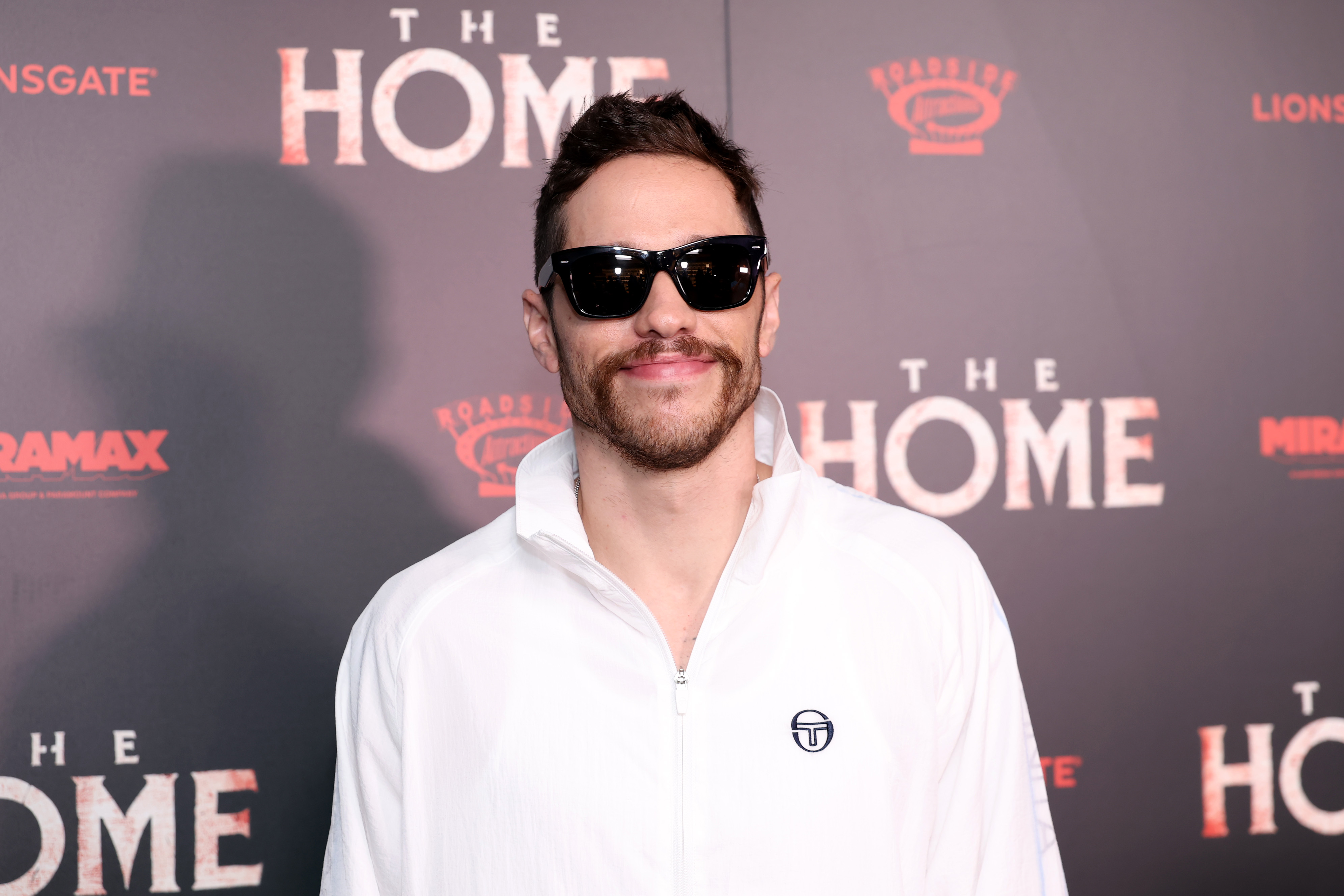 Pete Davidson in sunglasses wearing white. 