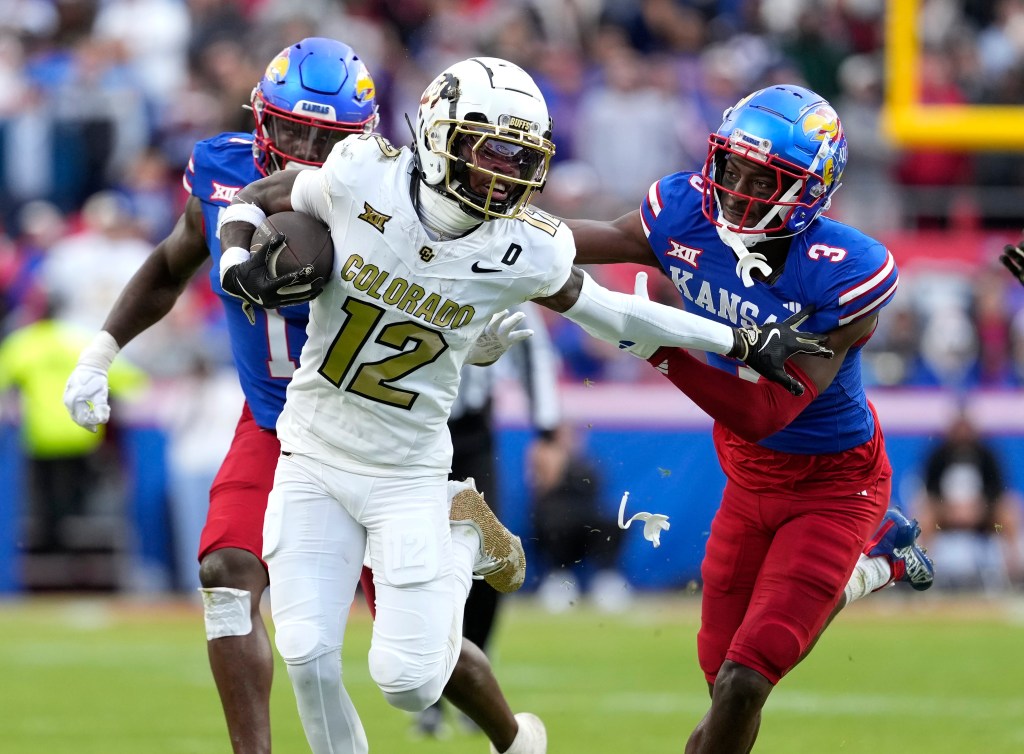 Wide receiver Travis Hunter #12 of the Colorado Buffaloes running with the ball against cornerback Mello Dotson #3 of the Kansas Jayhawks during a football game at Arrowhead Stadium.