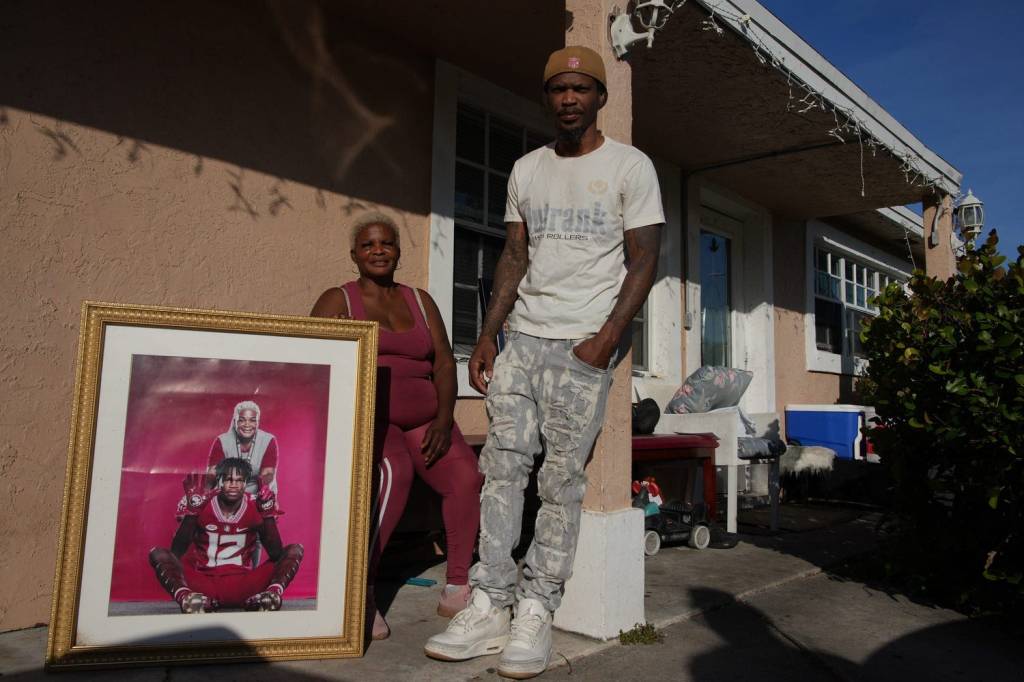 Shirley Hunter holding a photo of her grandson Travis Hunter Jr. and his father Travis Hunter, Sr. outside her home in Florida.