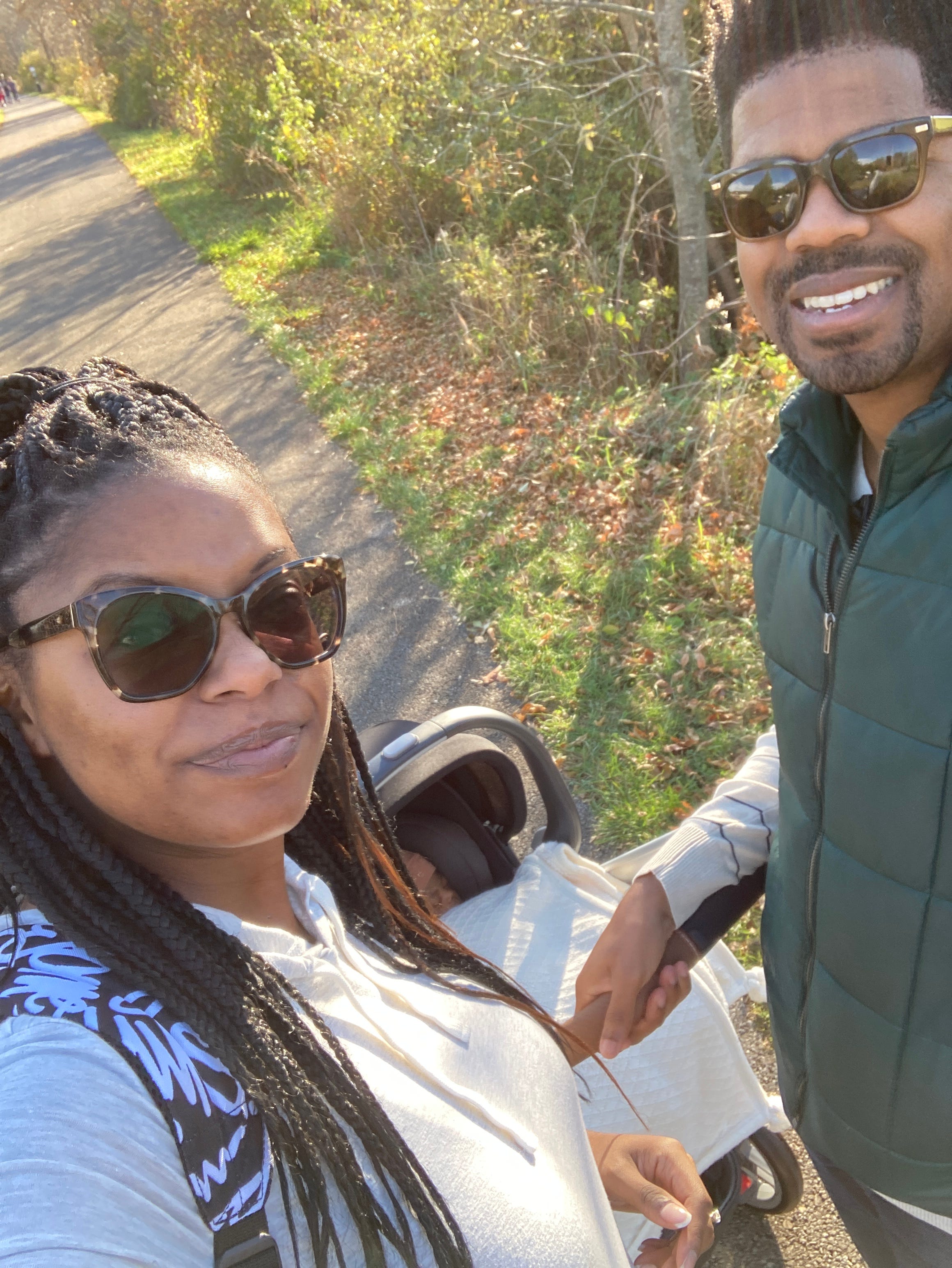 A woman and man walking their baby in a stroller outside