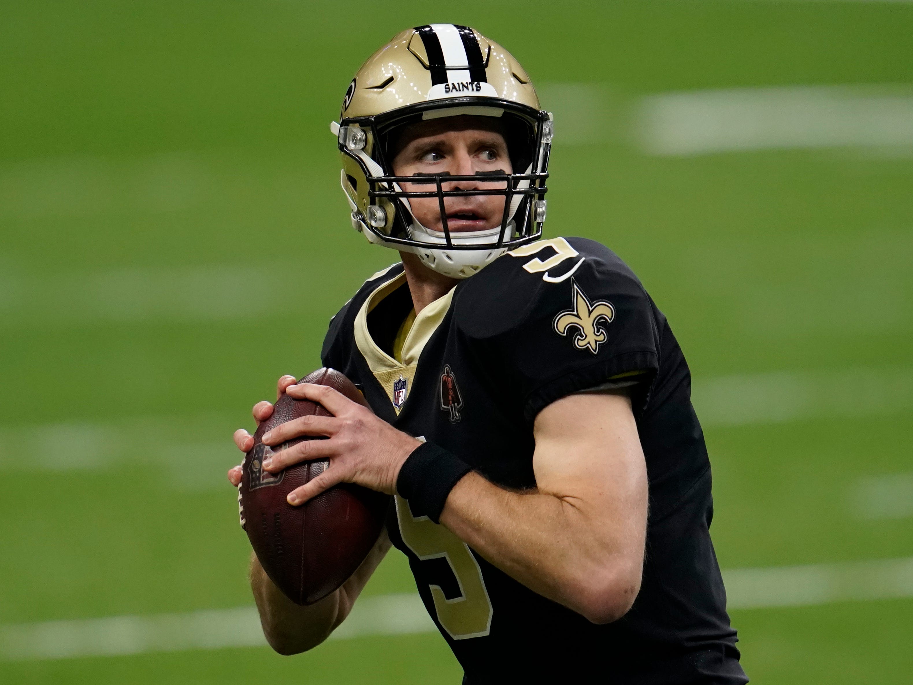 Drew Brees, #9 of the New Orleans Saints, preparing to make a pass during warmups before a 2021 wild-card playoff game against the Chicago Bears.