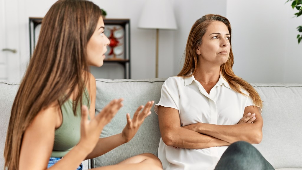 A mother and daughter argue on a sofa.