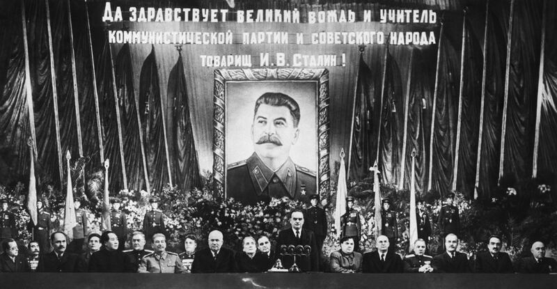 While a huge portrait of the guest of honor beams down from the rear like