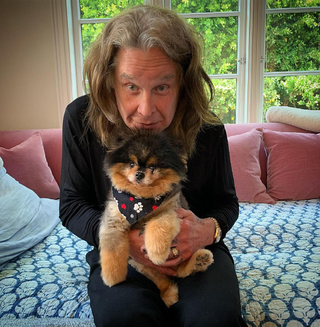 Ozzy Osbourne cradles a tiny dog. 