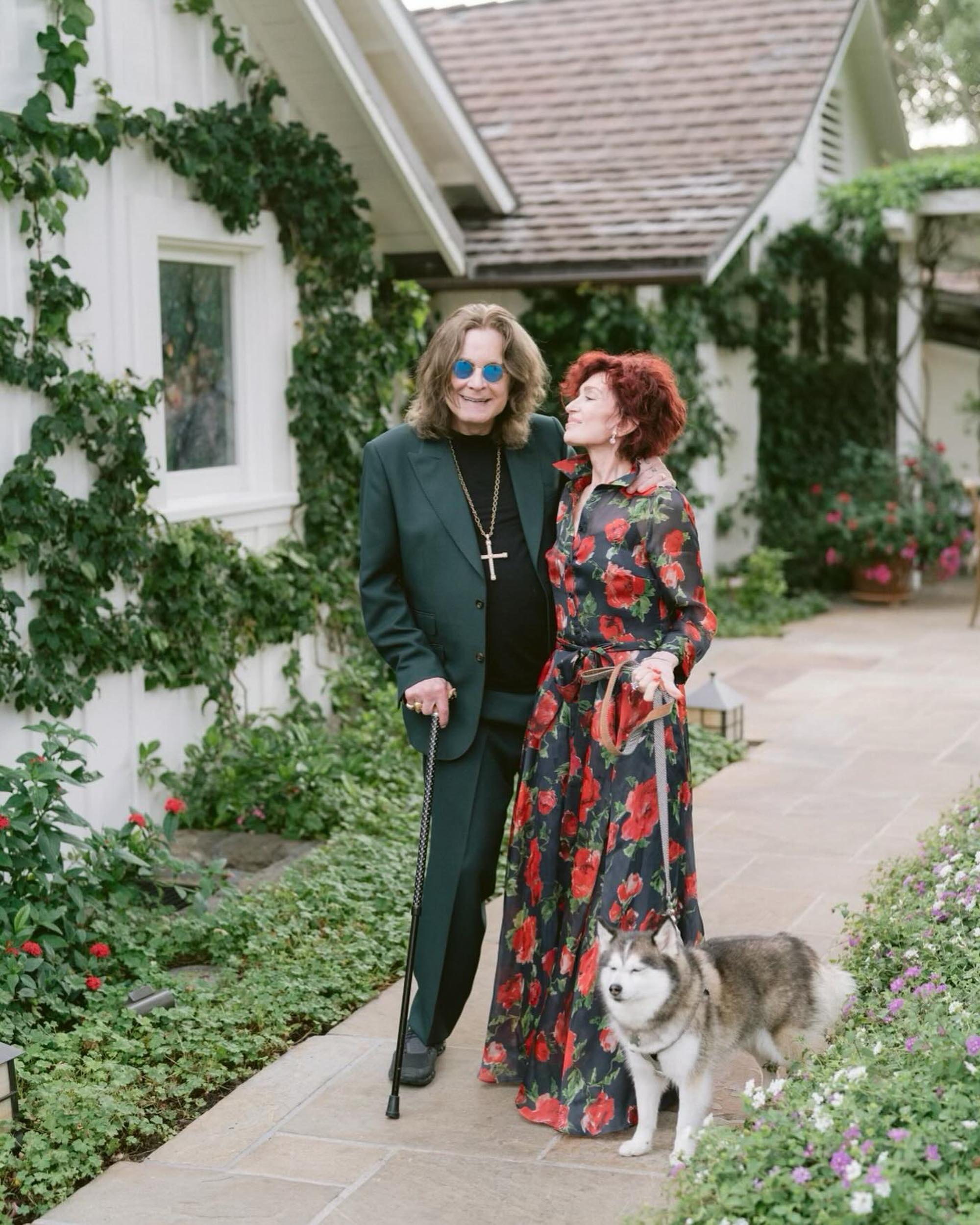 Ozzy and Sharon Osbourne pose in front of a house. 