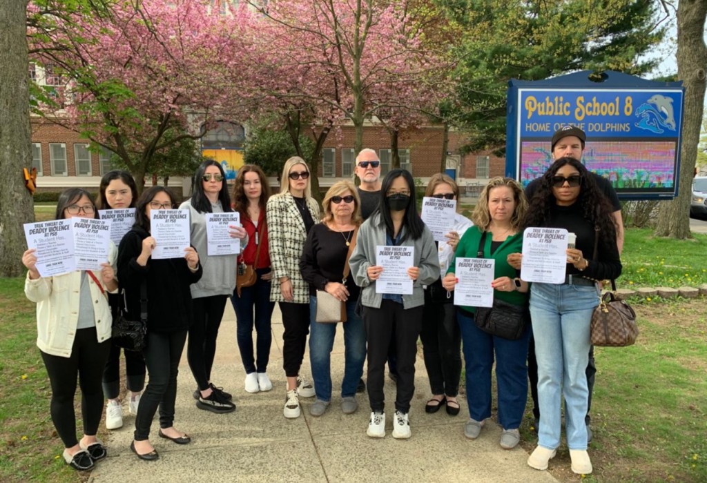 Parents protesting outside PS 8 in Staten Island, holding signs about a student's violent behavior.