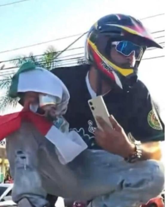 Man in helmet looking at phone, wanted for assaulting a federal officer.
