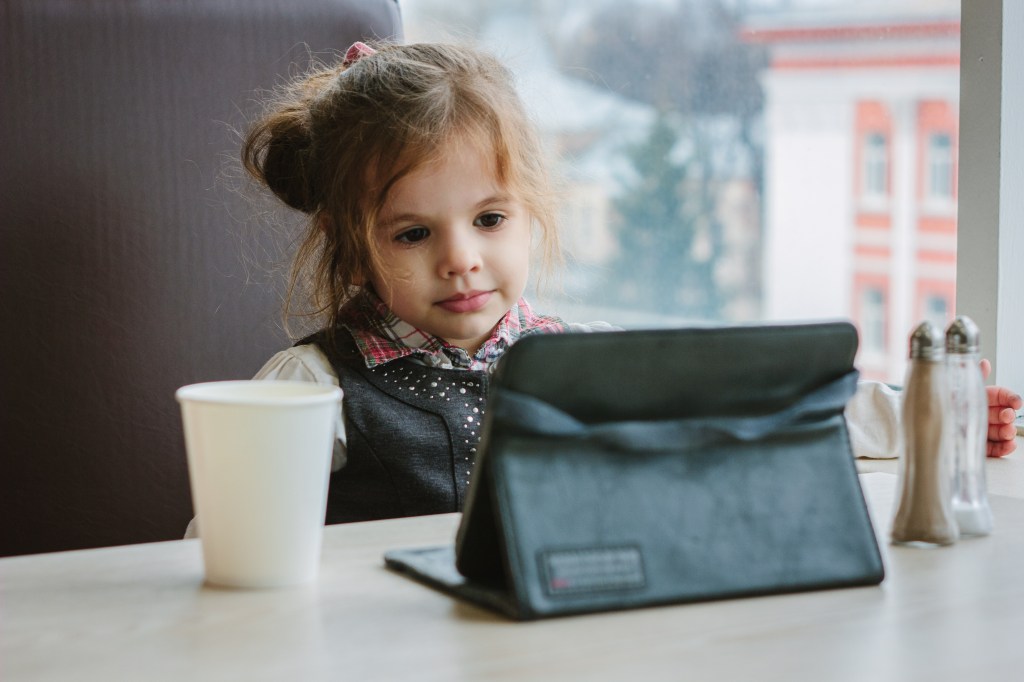 Little girl on a tablet at a restaurant. 