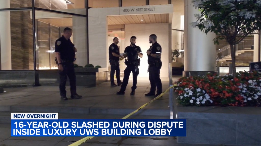 Police officers at the scene of a stabbing in a building lobby.