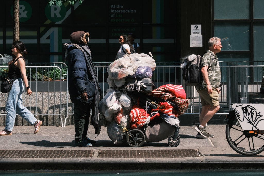 A homeless person with a cart full of belongings stands near the Port Authority Bus Terminal in Manhattan.