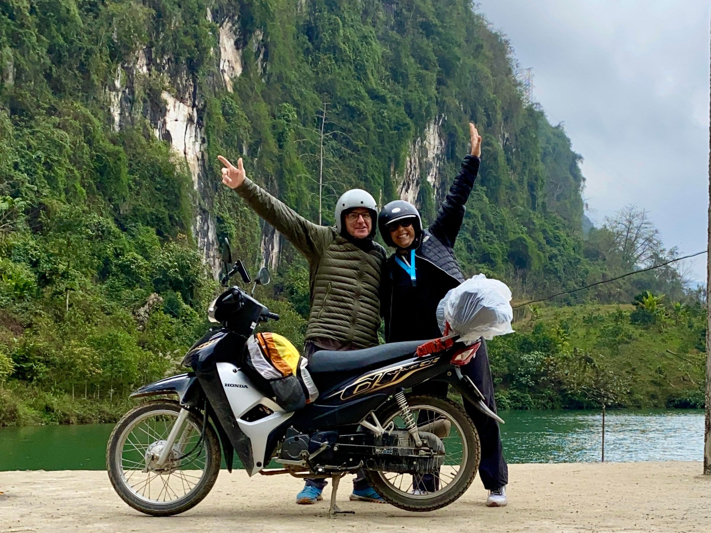 Cindy Sheahan (right) and her boyfriend in front od a mountain, standing behind a motorcycle.