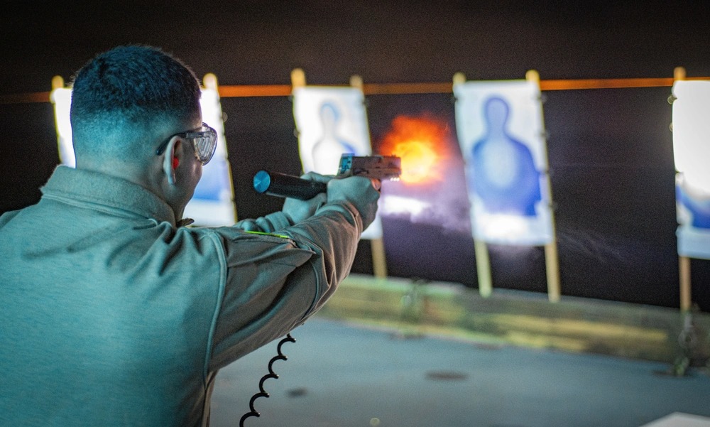 Person firing an M18 handgun at a shooting range.