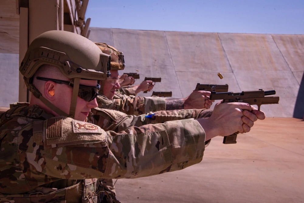 Air National Guard members fire handguns at a target range.