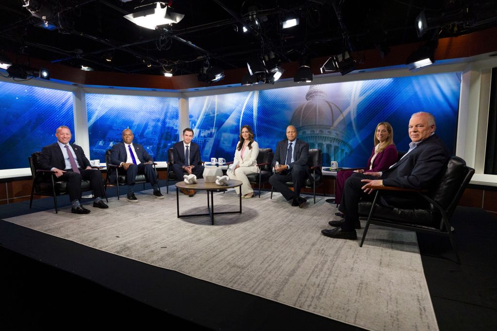 Six gubernatorial candidates seated for a televised discussion.