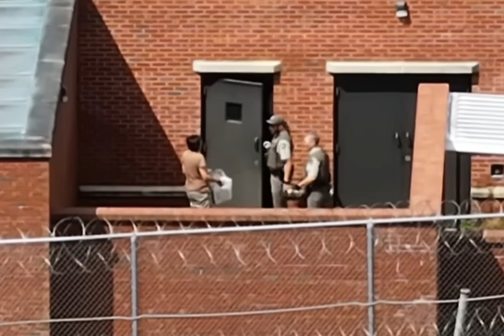 Maxwell carries the box inside the prison after being uncuffed by two guards. 