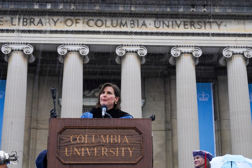 Columbia University's acting president speaking at a commencement ceremony.