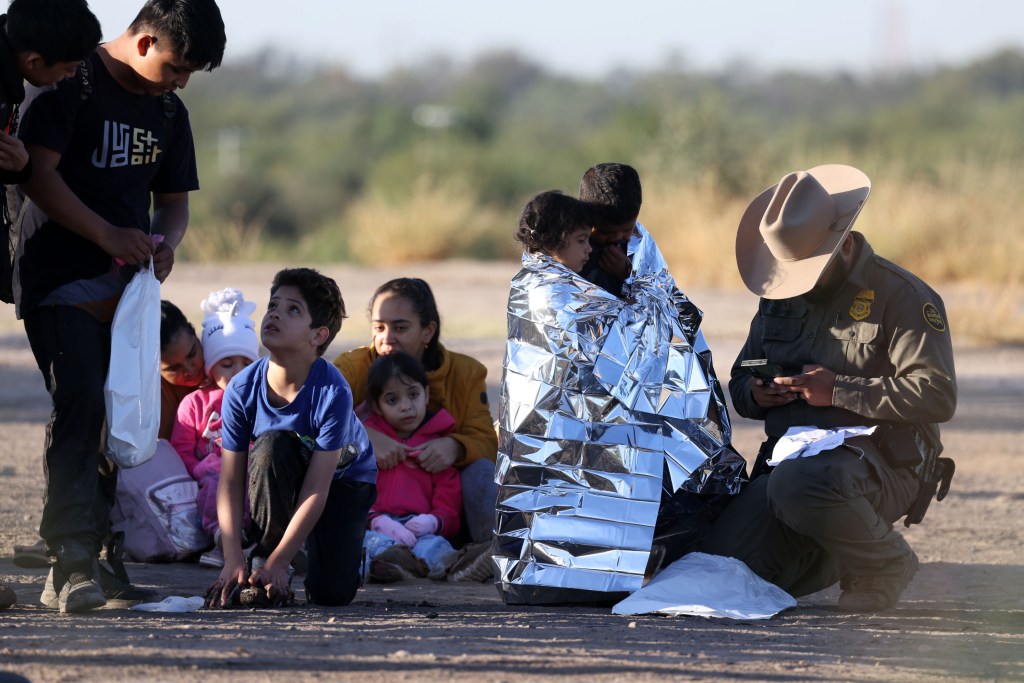 Migrant group, including women and children, crossing the US border.