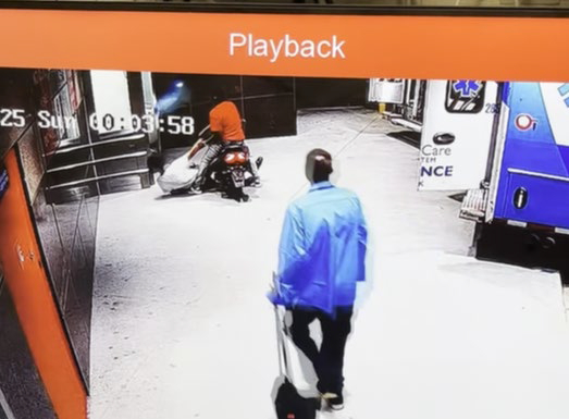 Surveillance footage showing a person on a motorcycle and another person walking away.
