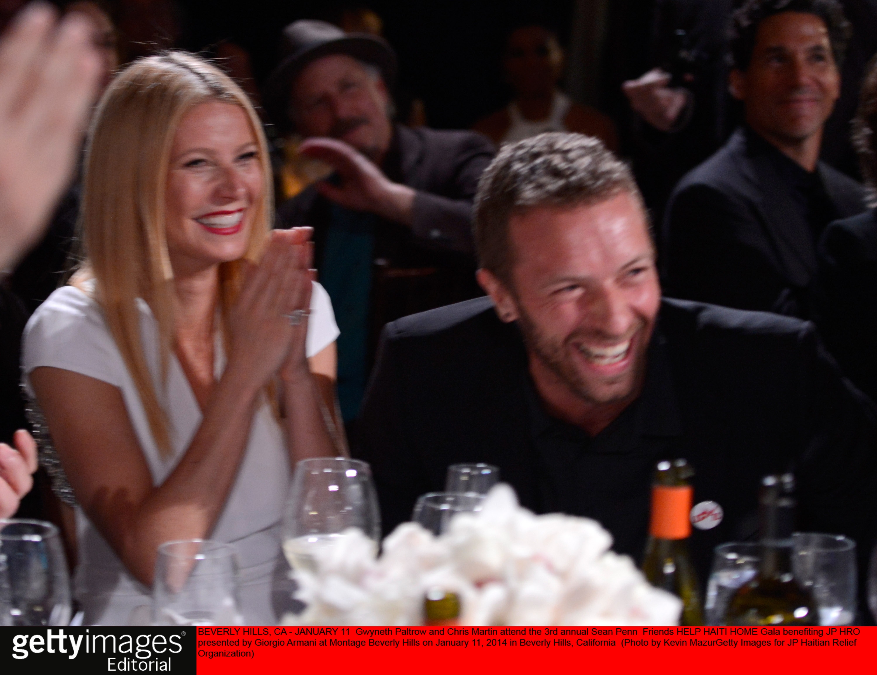 Gwyneth Paltrow and Chris Martin laugh at a table. 
