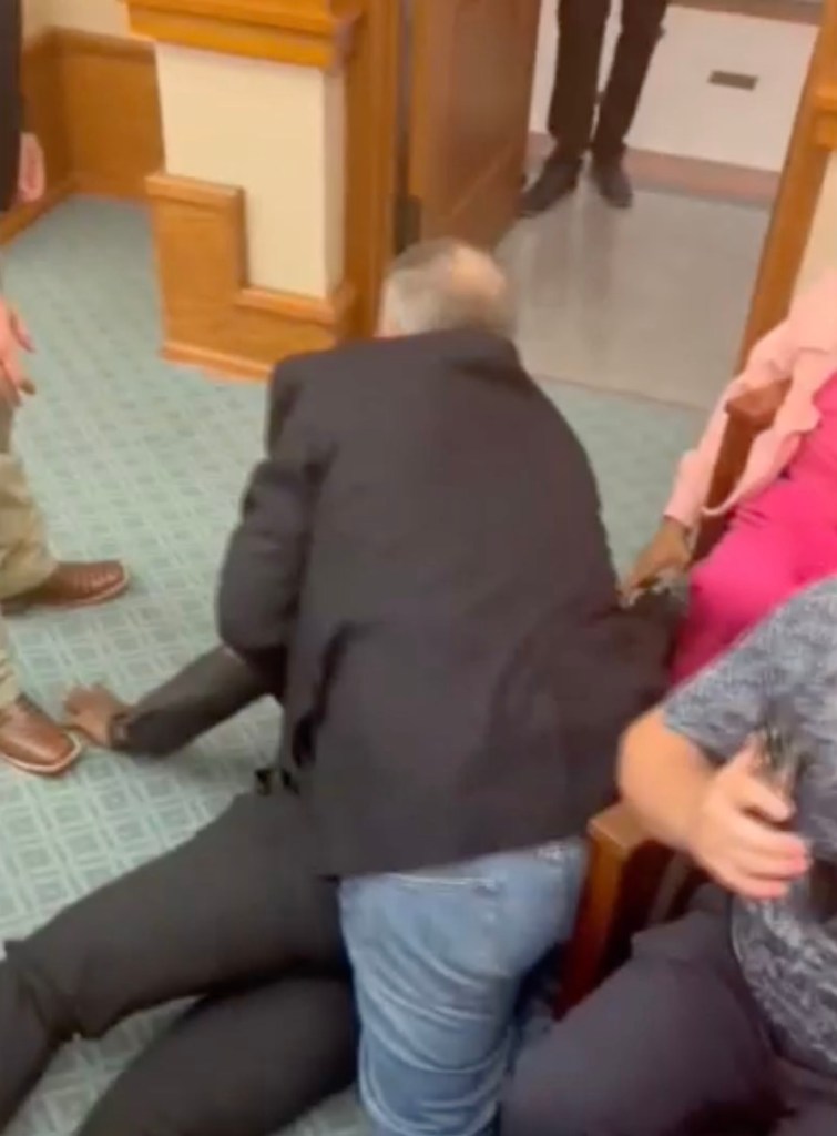 A man being arrested at a redistricting hearing.