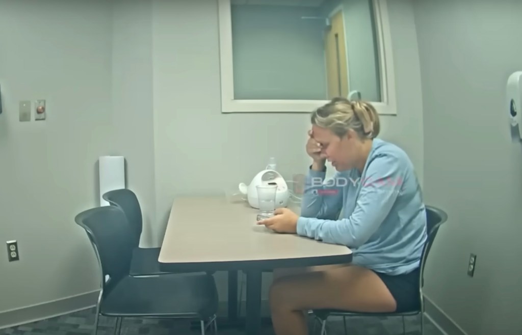 Bodycam footage of a woman sitting at a table during an interview.