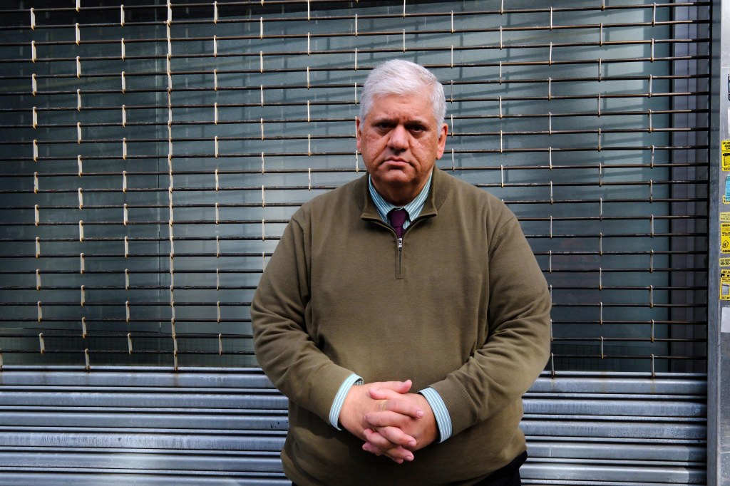 Man standing in front of a metal security gate.