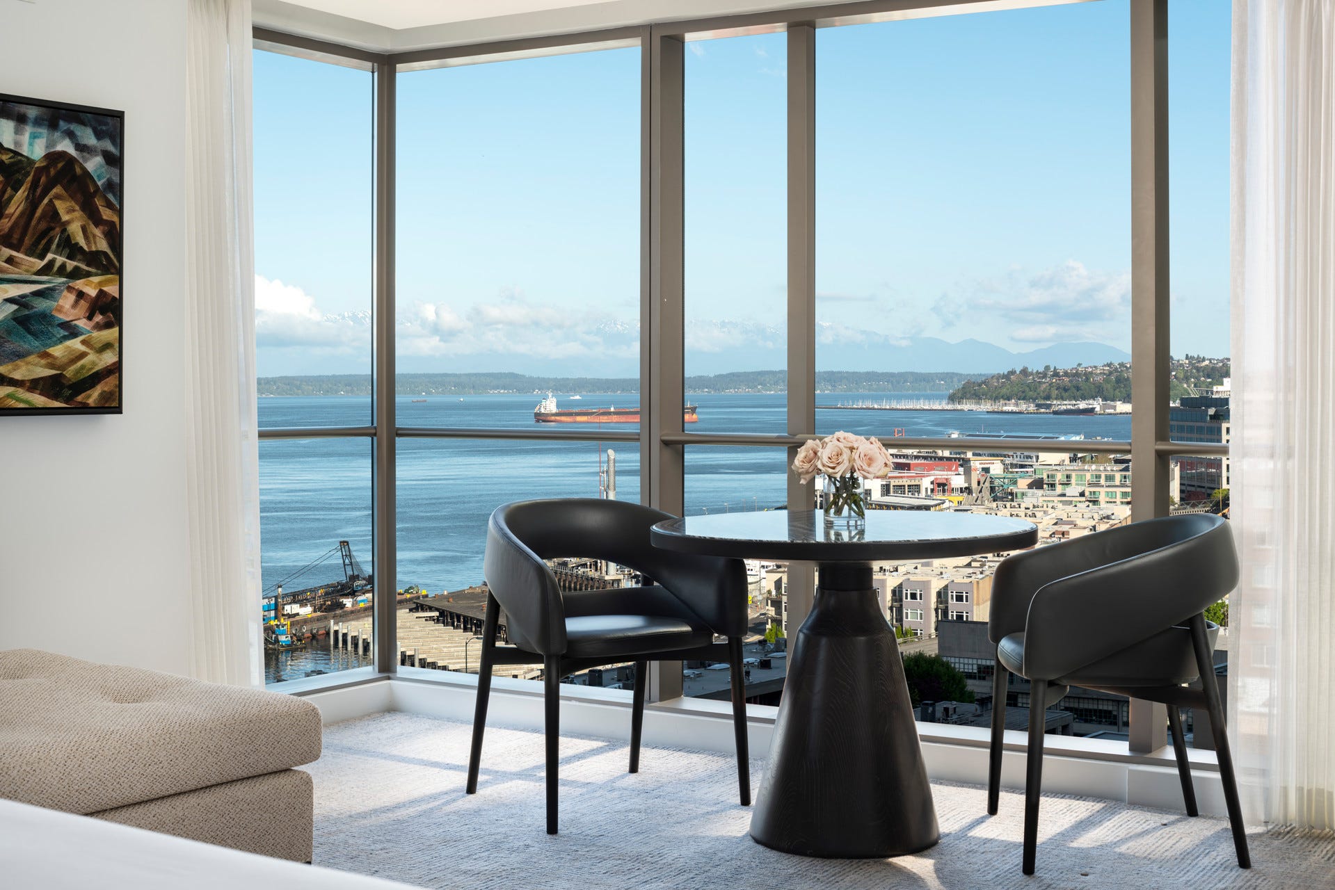 Inside a Four Seasons room with a table and chairs in front of florr-to-ceiling windows showing the bay outside