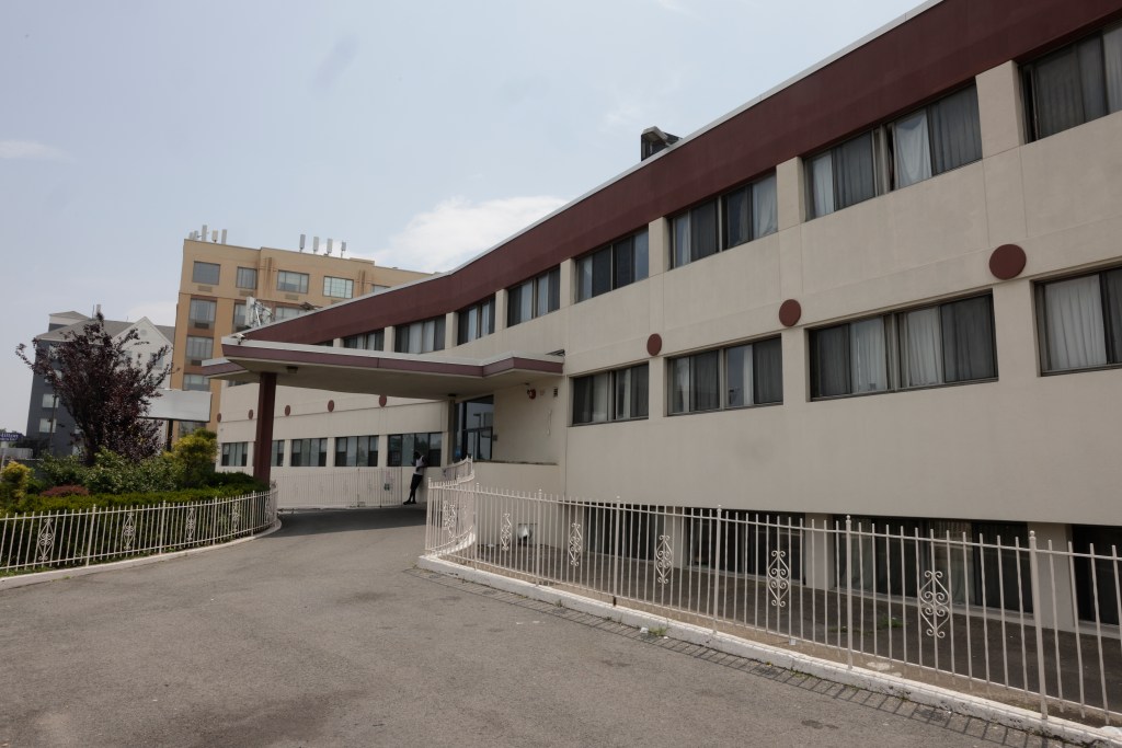 Exterior of a beige multi-story building with a maroon roofline.