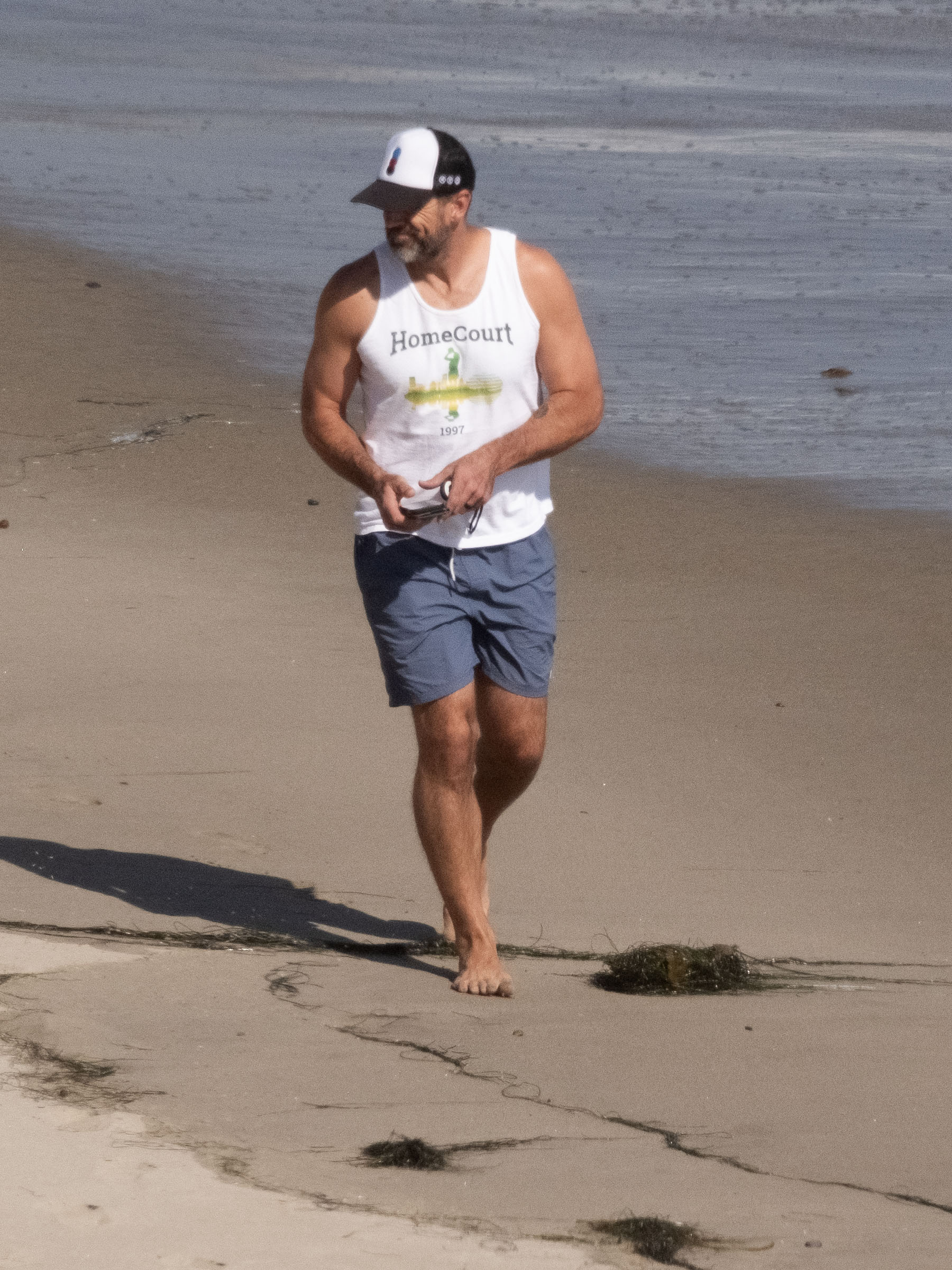 Aaron Rodgers walks on the beach. 