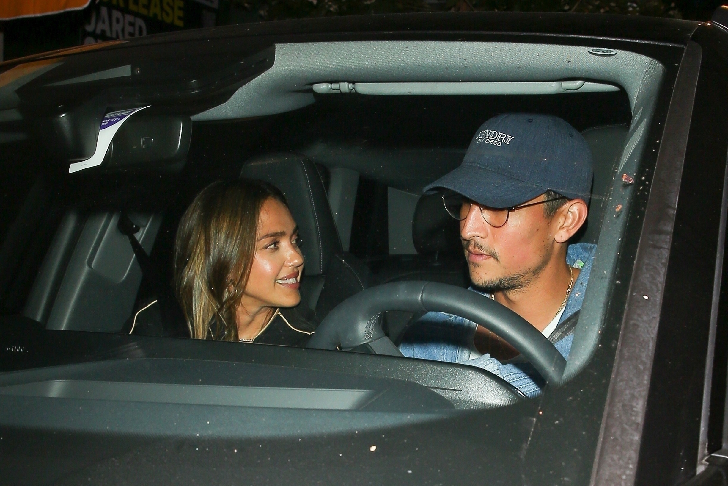 Jessica Alba smiles at Danny Ramirez in a car. 