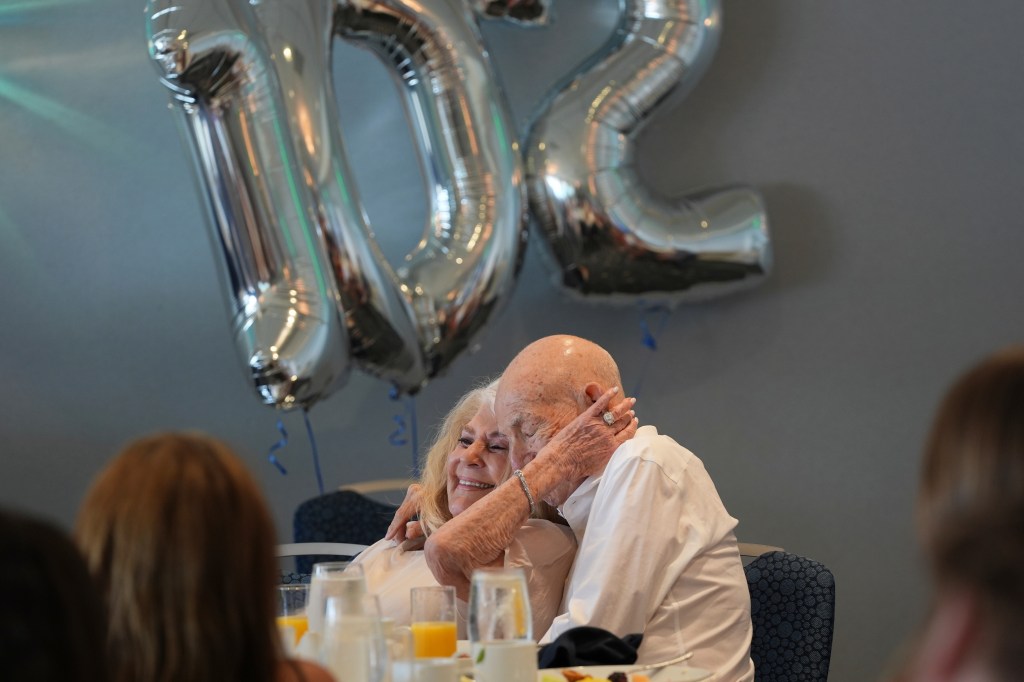 A woman embraces her husband at his 102nd birthday celebration.