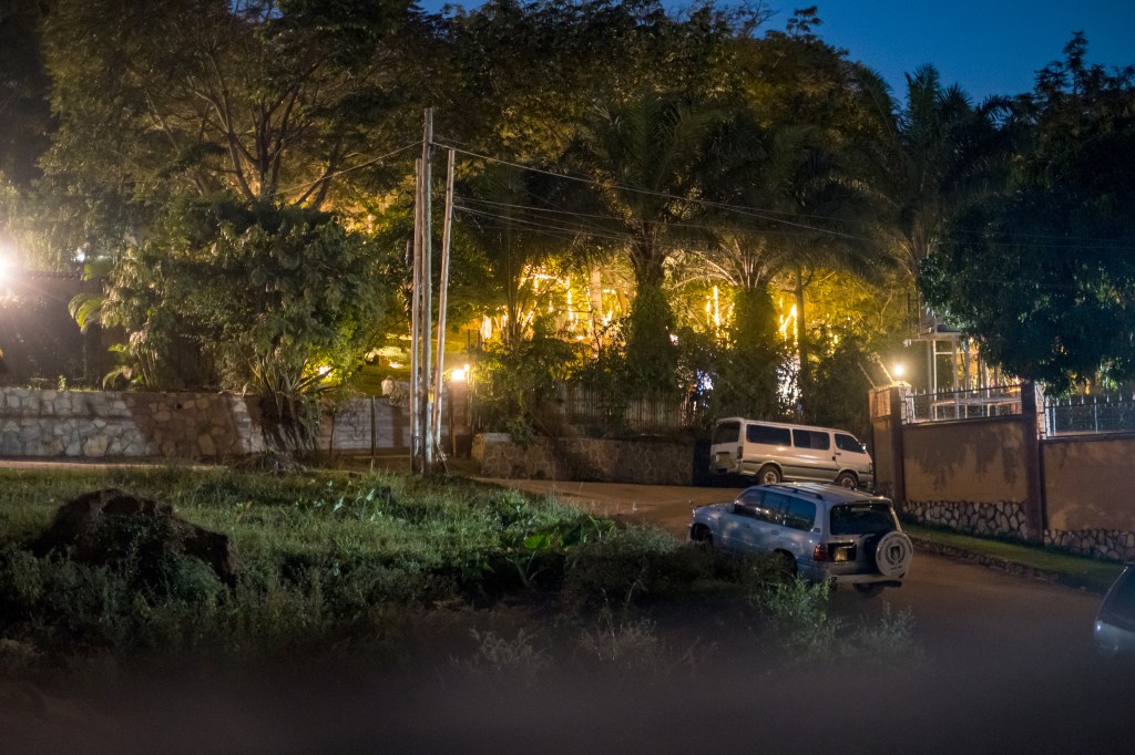 Nighttime view of two cars parked near a brightly lit building.
