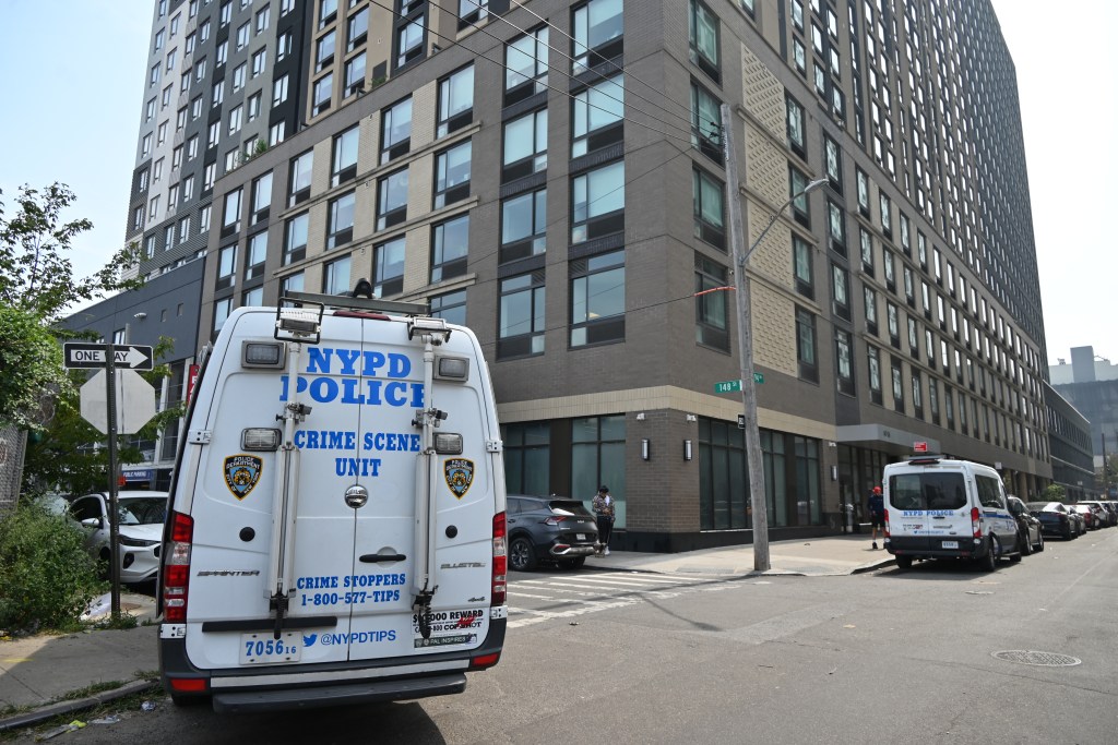 NYPD crime scene unit van parked outside an apartment building in Queens, NY.