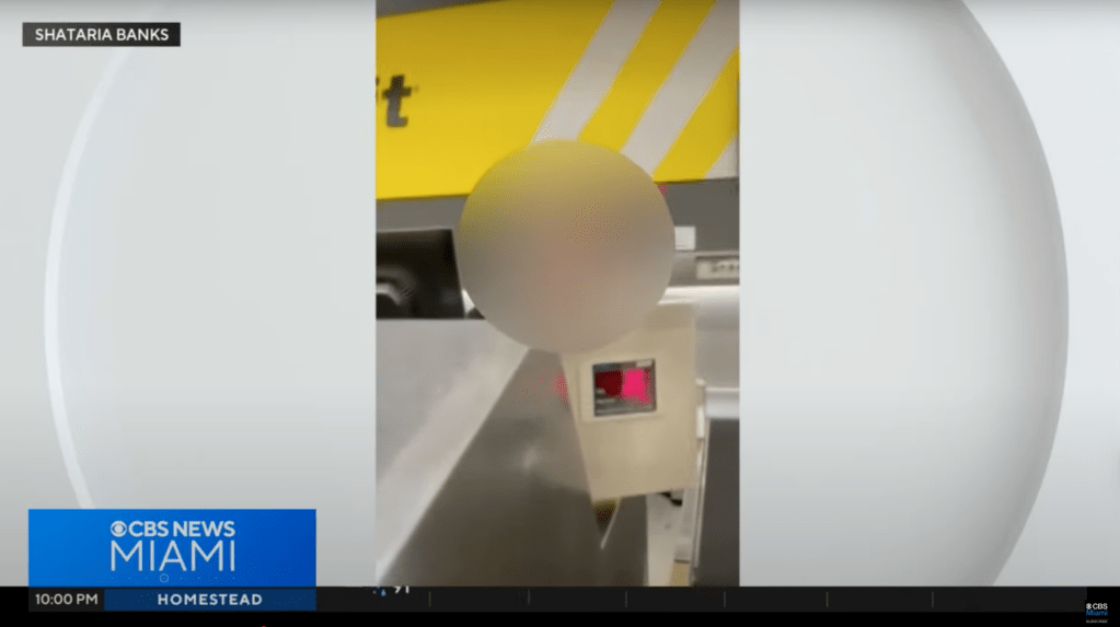 Screenshot of a person using a self-checkout kiosk, blurred for privacy.