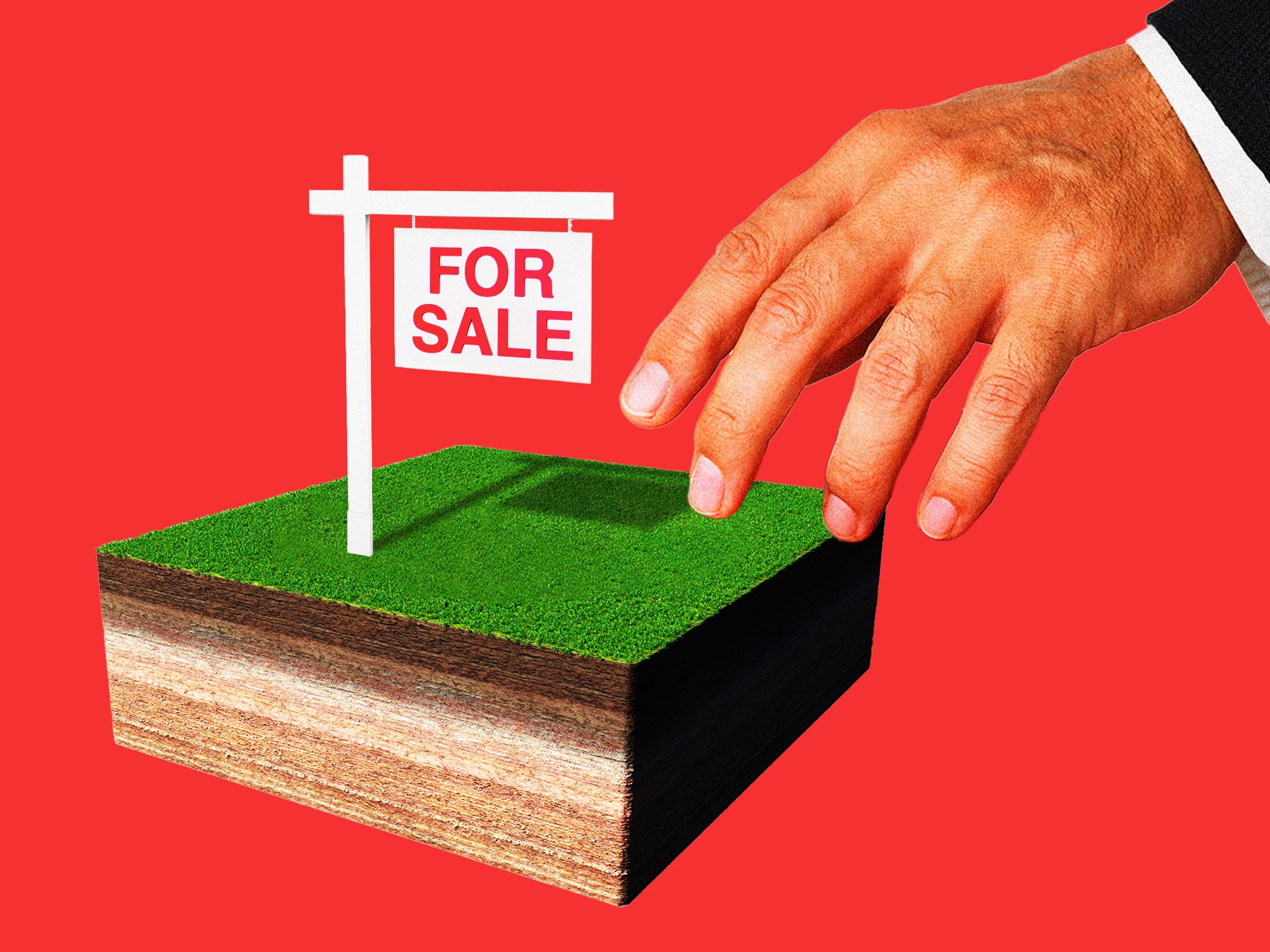 A businessman's hand reaching for a plot of land that is for sale
